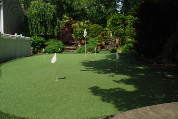 Augusta Synthetic grass golf green with flags in a landscaped backyard