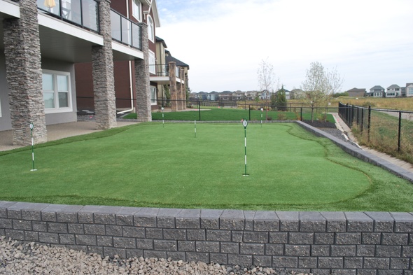 Augusta residential backyard putting green grass near modern home with golf flags