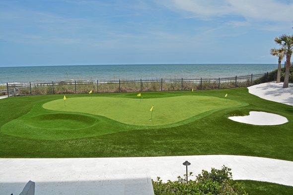 Augusta Synthetic grass golf green by the sea with yellow flags and a sand bunker