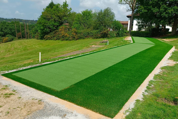 Augusta Outdoor tee line consisting of one continuous green synthetic grass strip surrounded by trees